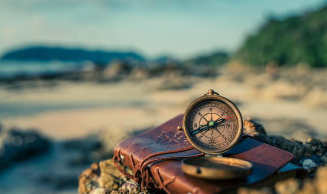 Ein Kompass und Buch am Strand