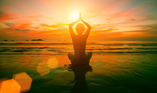Frau sitzt am Strand meditierend